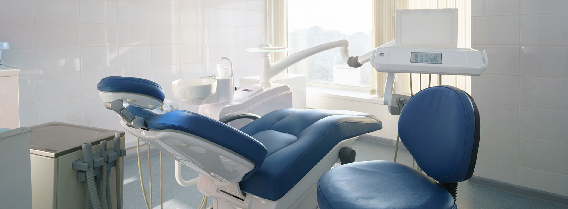 The image shows a modern dental clinic interior with various pieces of equipment, including a dental chair and an X-ray machine.