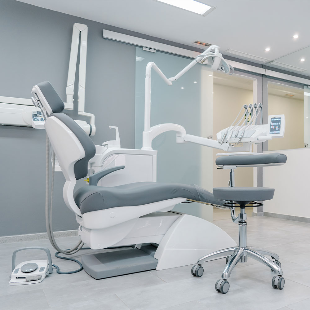 The image shows a dental office interior with a dental chair, a dental light, and various dental equipment.